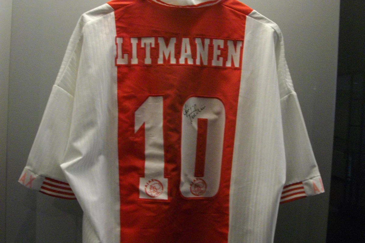 Bagian belakang kostum Ajax putih dengan panel merah, nama LITMANEN dan nomor 10 bertanda tangan, di etalase museum