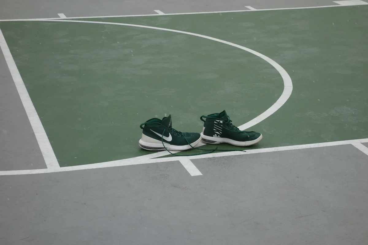 Sepasang sepatu basket Nike Air Max Dominate hijau tua di garis lapangan basket outdoor