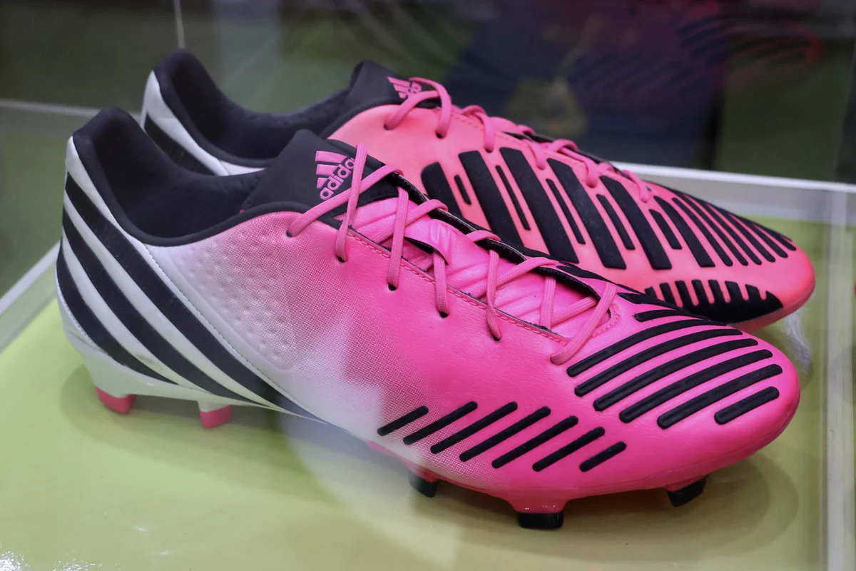 Sepasang sepatu bola Adidas Predator LZ merah muda putih dengan pola garis hitam di etalase