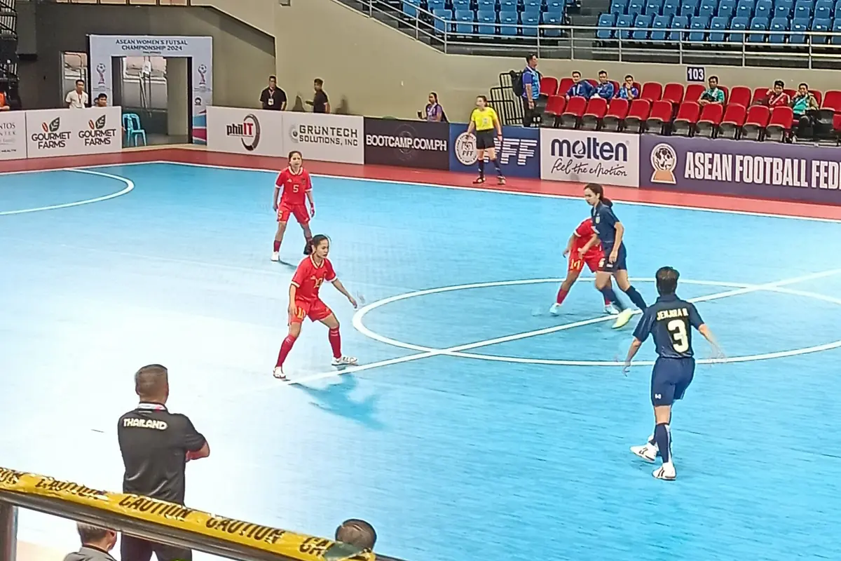 Pemain futsal putri berduel memperebutkan bola di lapangan interior biru pada Kejuaraan Futsal Putri ASEAN 2024