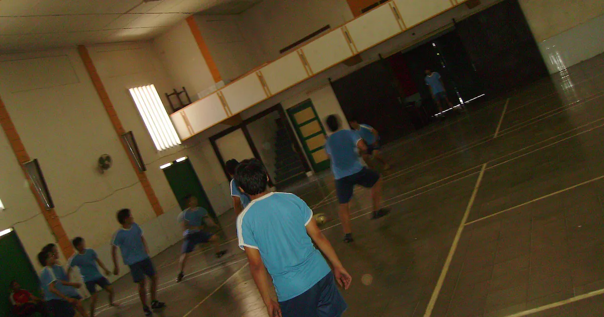 Siswa SMA bermain futsal di lapangan aula sekolah berlantai keramik
