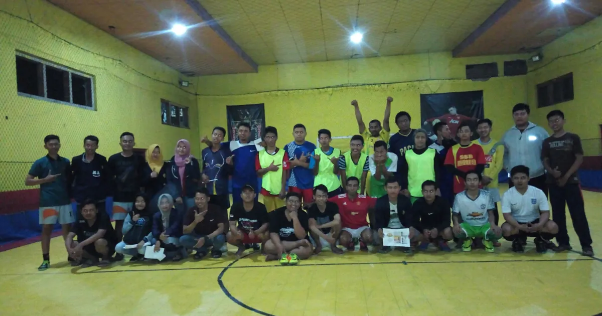 Puluhan pemain futsal amatir putra dan putri berfoto bersama di lapangan futsal interior berlantai kuning