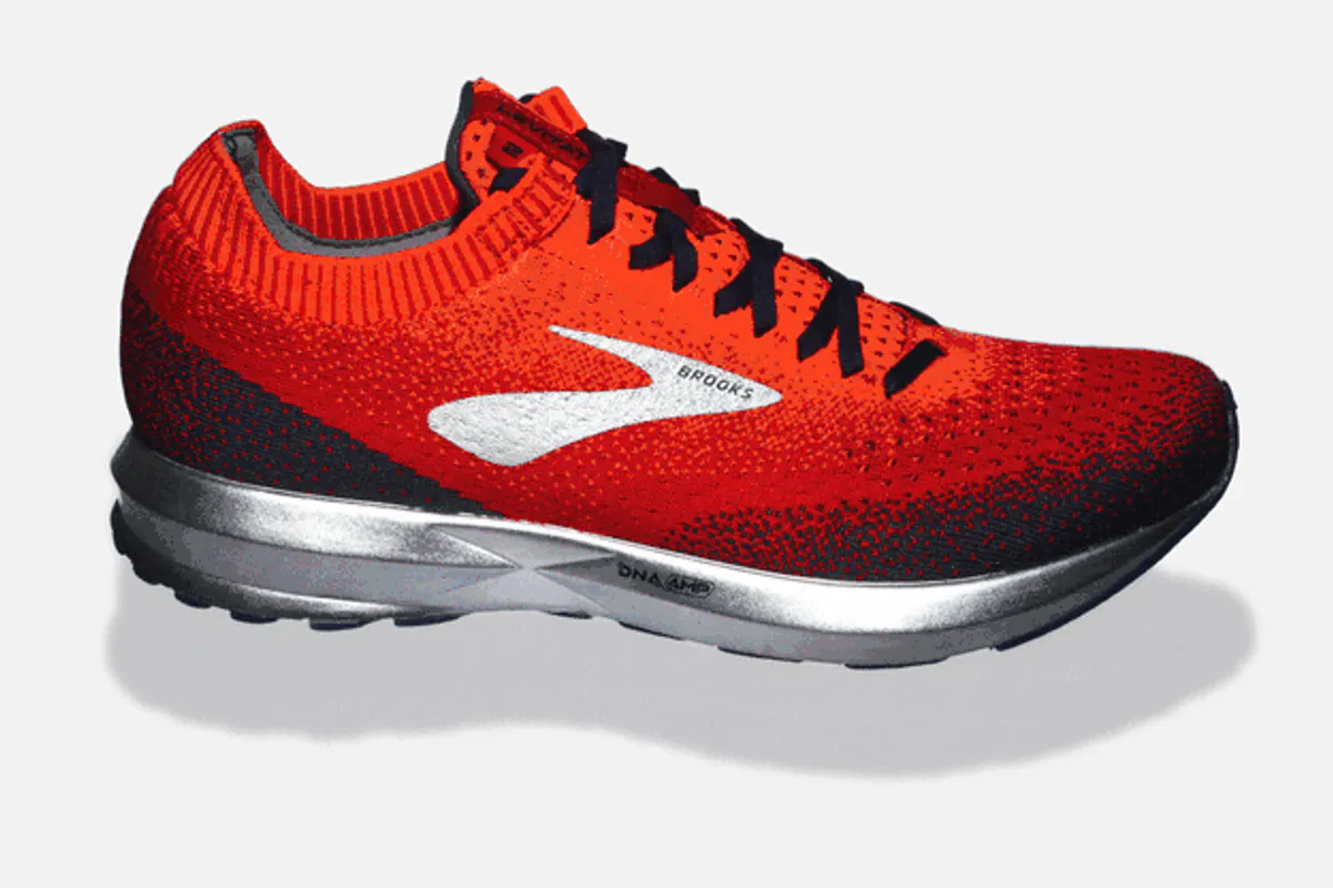 Sepatu lari Brooks merah dengan upper rajut, logo Brooks putih, dan midsole perak