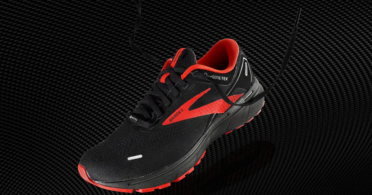 Sepatu lari Brooks Ghost 14 GTX hitam dengan aksen merah di latar gelap